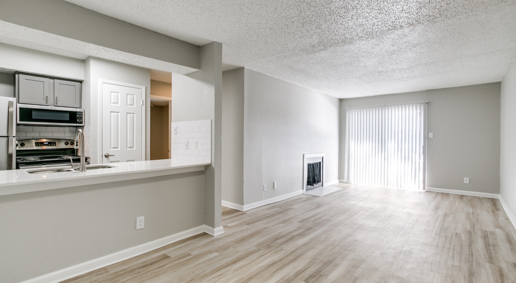 an empty room with hardwood floors and a white kitchen at The  Holden